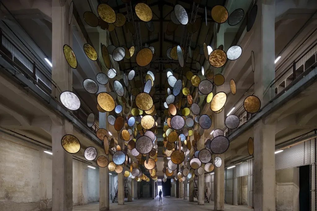 Conversion of Previous Train Manufacturing Facility into Illumination Artwork Featuring Suspended Gold and Silver Disks