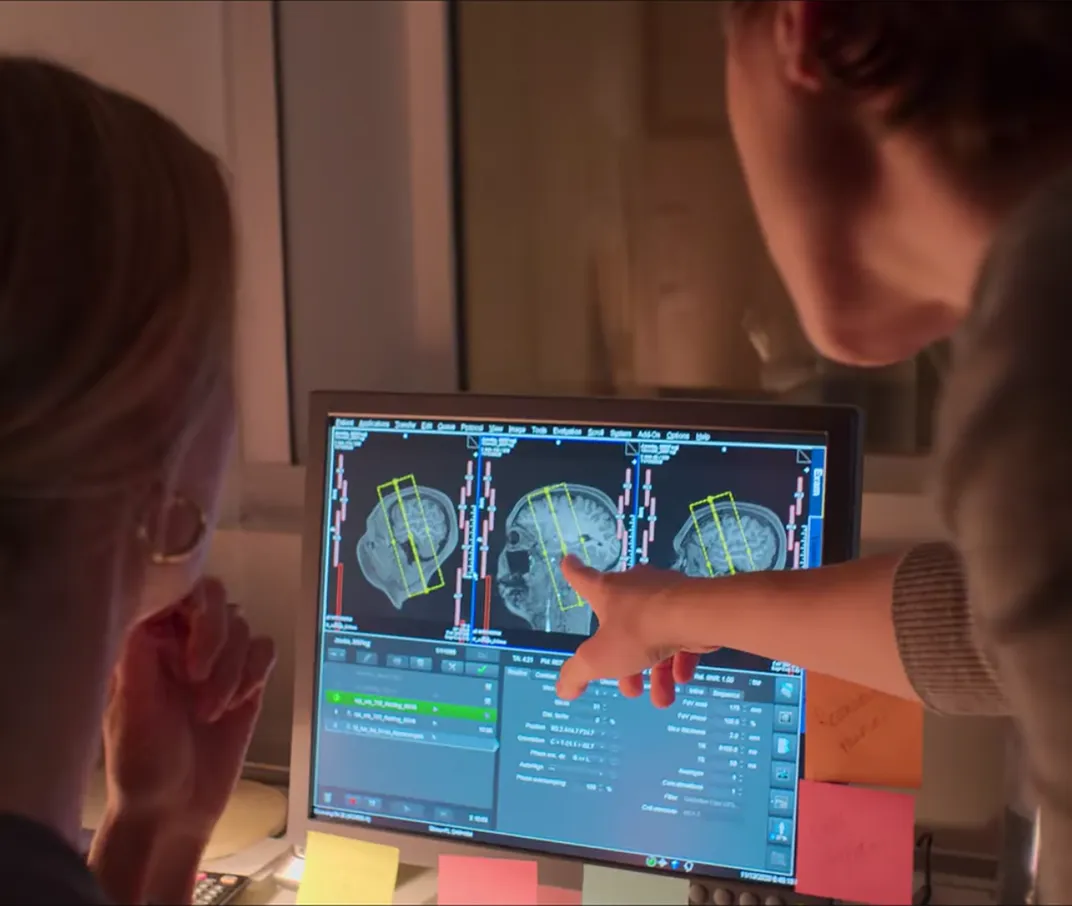 researchers examine brain scans on a computer display